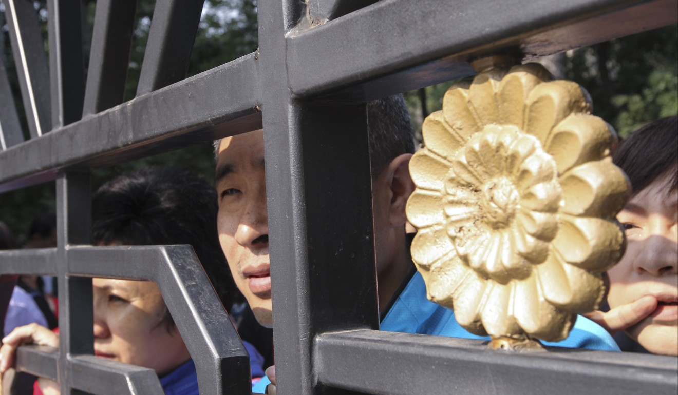 032 Parents look into the school through gate fence while their children taking part in the Gaokao national college entrance exams at Beijing No