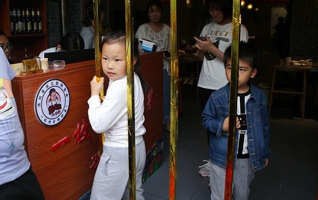 A girl attempts to squeeze through the narrowest bar at the restaurant in Shandong province