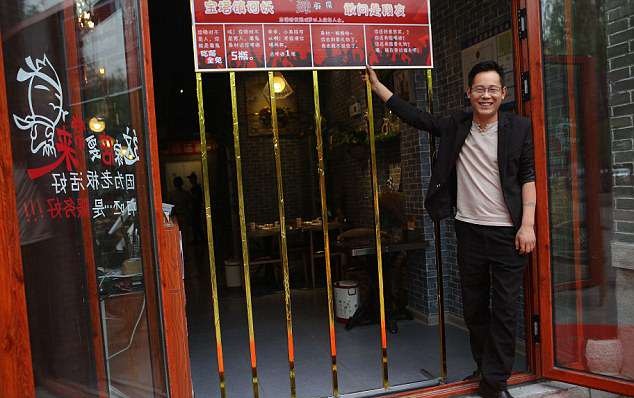 Restaurant manager Mr Liu shows the narrow metal bars that serve as a gate to the restaurant