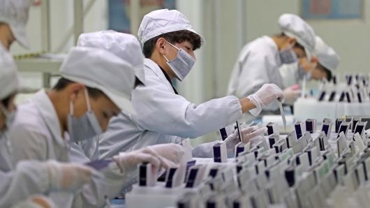Workers are seen at a production line manufacturing solar photovoltaic components at a factory in Huzhou