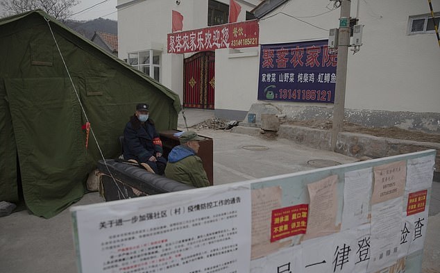 Villagers are pictured wearing masks and guarding at a checkpoint in rural Beijing