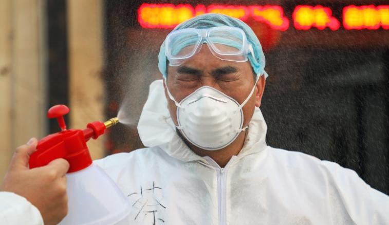 A colleague sprays disinfectant on a doctor in Wuhan