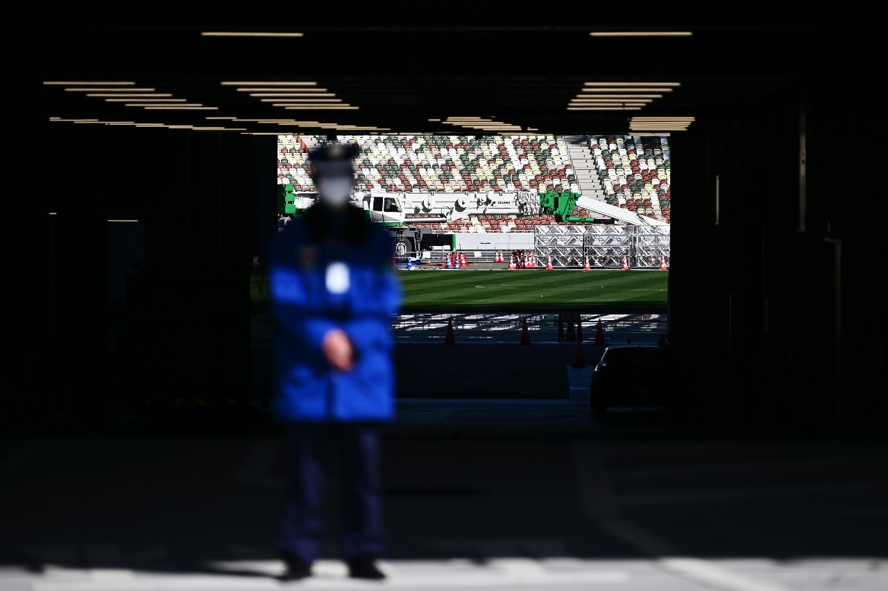 A masked security guard stands in front an entrance of the National Stadium venue of the upcoming Olympics in Tokyo on Feb.28