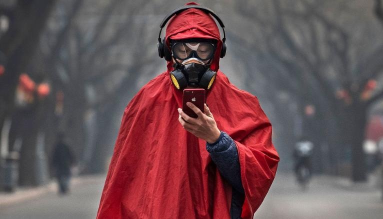 A person wears a protective mask goggles and coat as he stands in a nearly empty street in Beijing