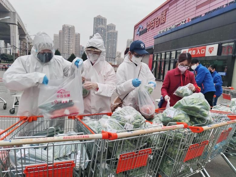 Community workers and volunteers wearing face masks sort and pack groceries from a supermarket purchased through group orders after supermarkets stop selling to individuals in Wuhan