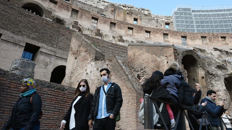 Tourists wearing respiratory masks visit the Coliseum in Rome