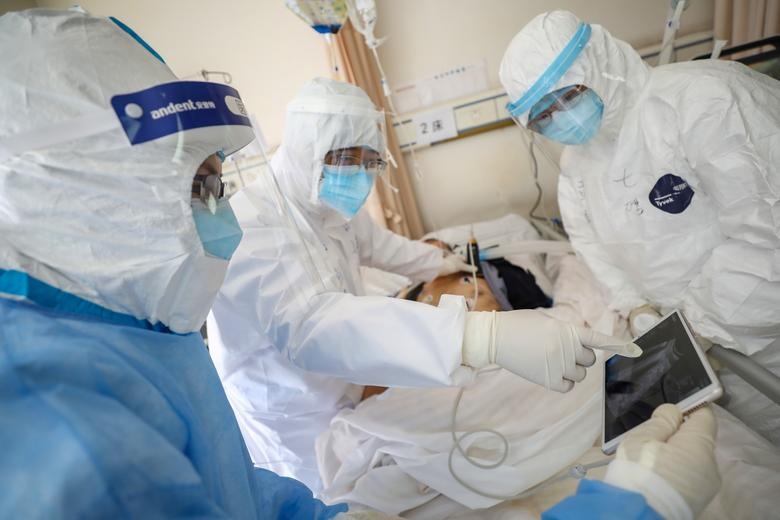 Medical workers in protective suits attend to a patient inside an isolated ward of Wuhan Red Cross Hospital in Wuhan