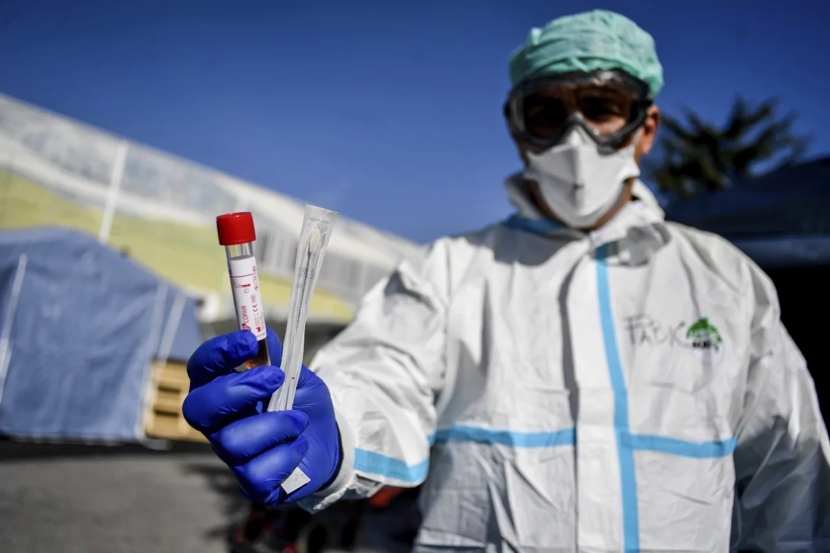 A medical worker holds out a test kit outside an emergency facility in Brescia northern Italy