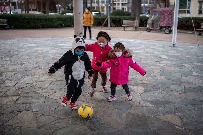 Children wearing protective facemasks play soccer in Beijing