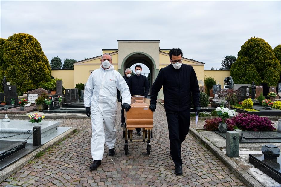 Pallbearers pull the coffin of a deceased person for a funeral ceremony into the cemetery of Grassobbio Lombardy on March 23 2020 in the absence of quarantined relatives