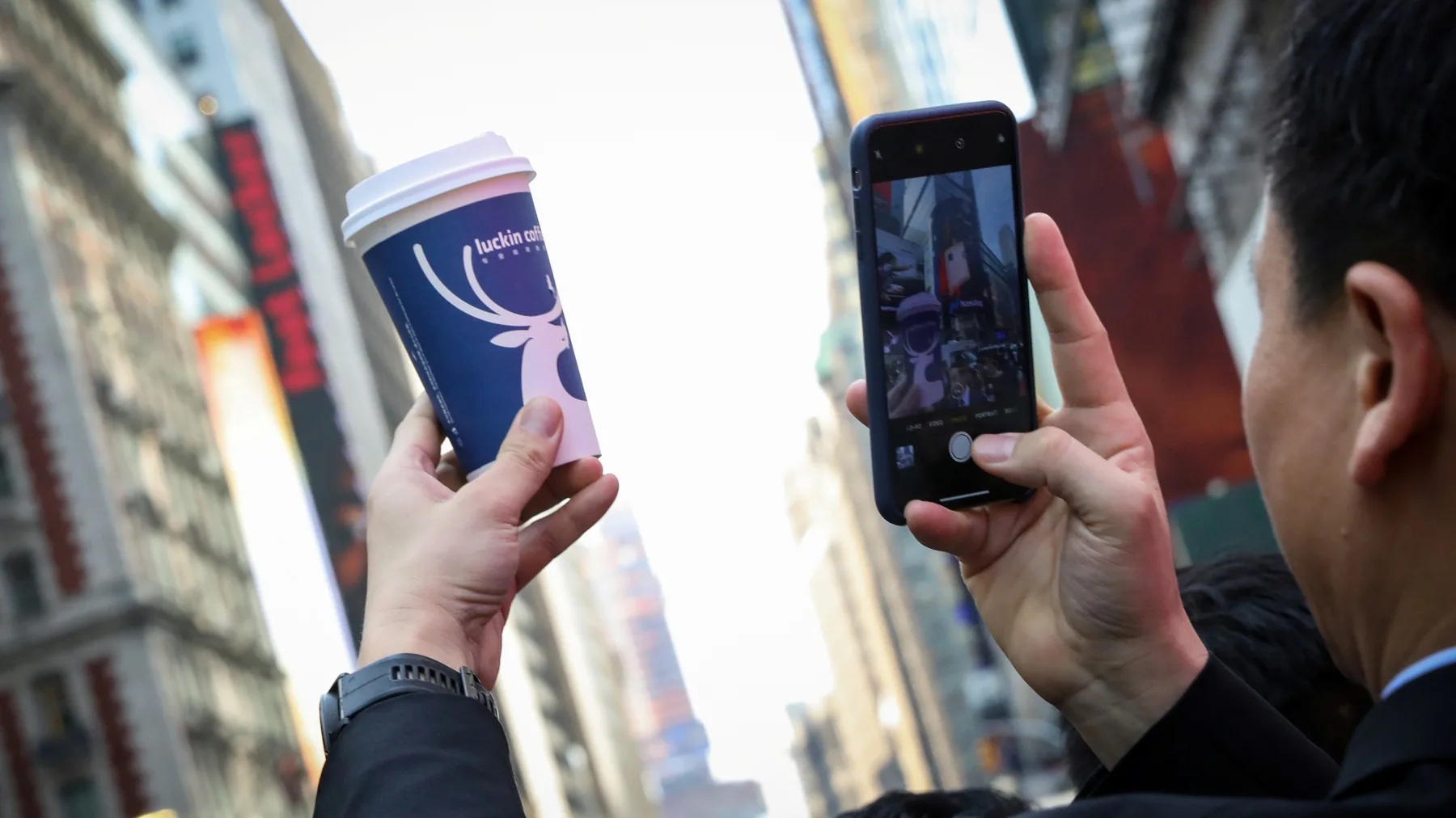 A Luckin Coffee executive photographs a cup during the companys initial public offering at the Nasdaq Market in May 2019