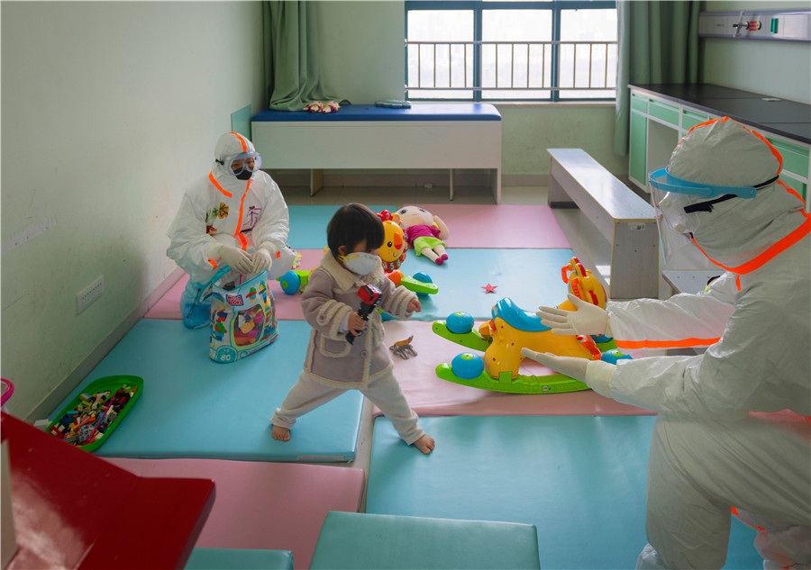 Two nurses play with a young patient in an isolation ward at the hospital on March 11