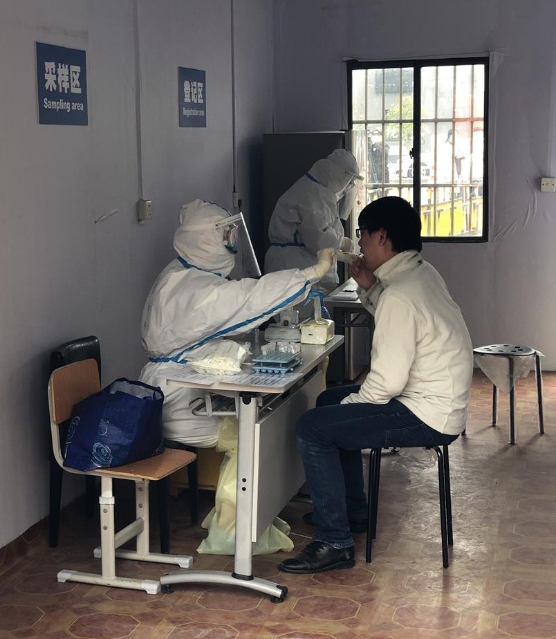 A medical staff collects throat and nose swabs from an employee newly returned to Shanghai in Putuo District