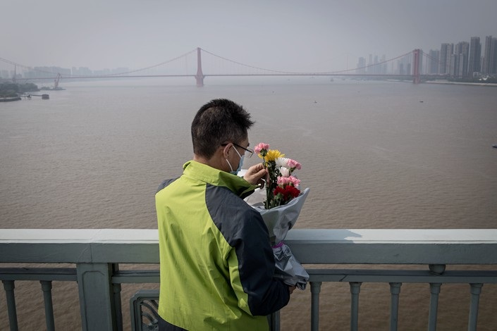 A resident prepares to throw flowers into the Yangtze River from a bridge in Wuhan to honor the dead on April 4