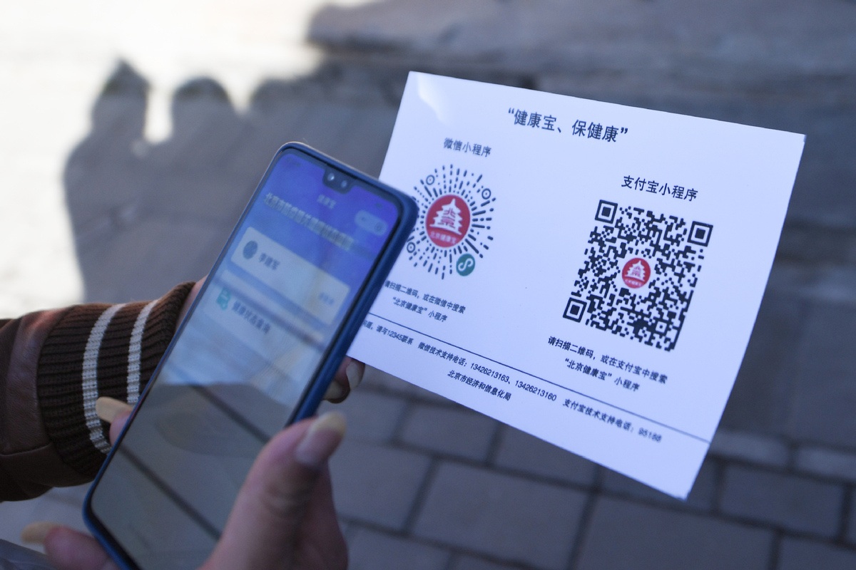 A resident scans a QR code of a mini program to report health information in Beijing