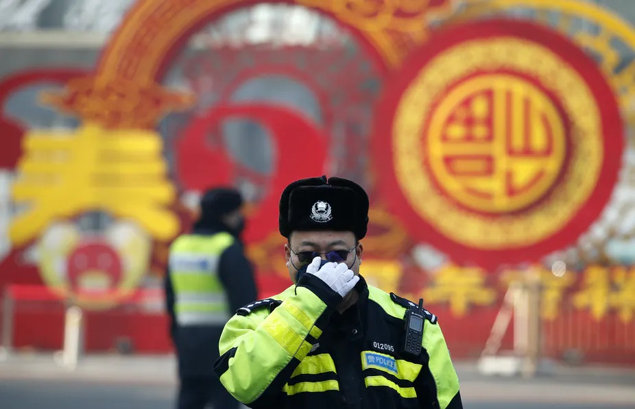 A police officer in Beijing adjusts his face mask which millions in China are using in hopes of preventing coronavirus infection