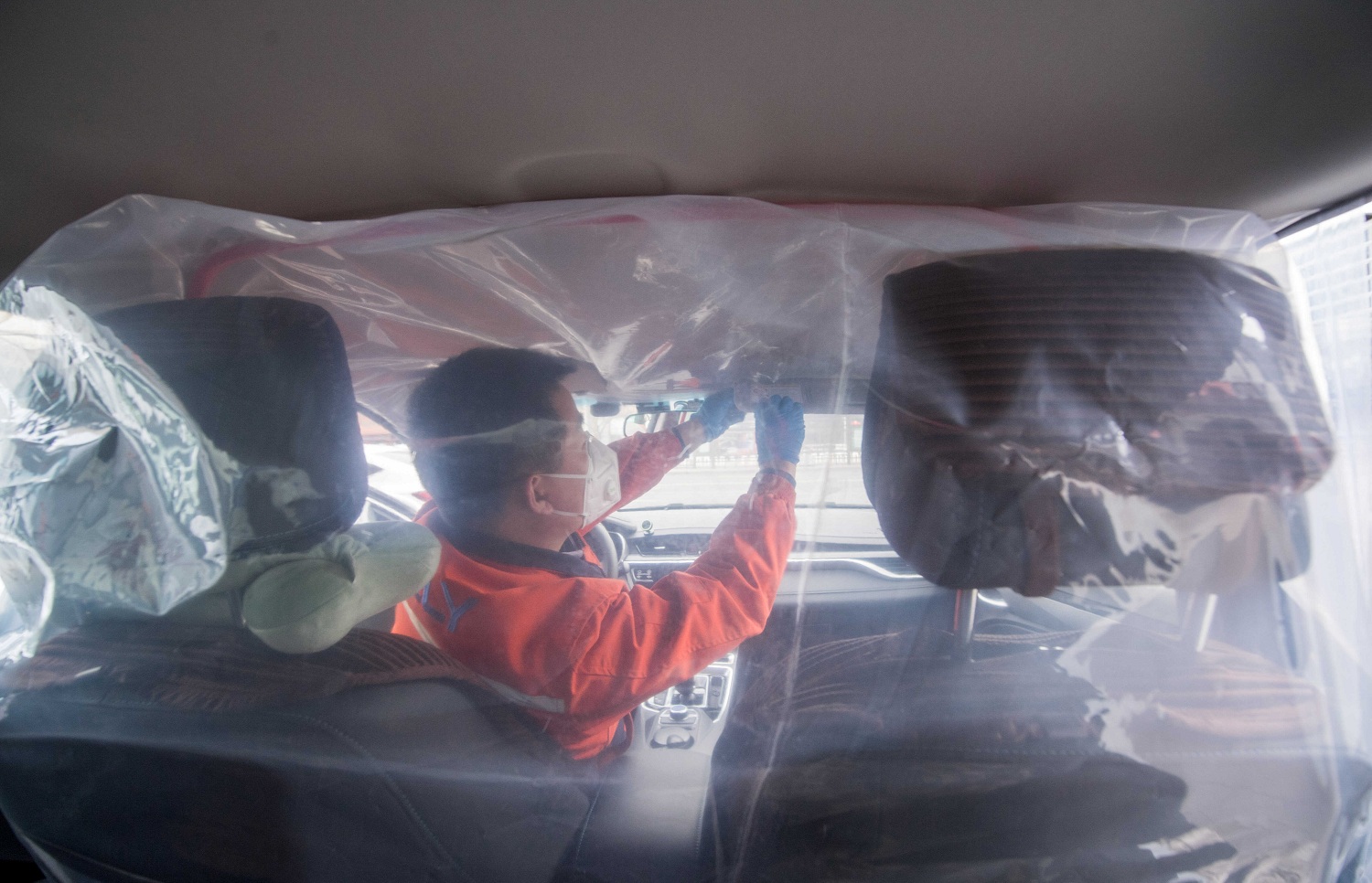A worker installs plastic film to separate the front seats from the back inside a vehicle for a car hailing service as the country is hit by an outbreak of the novel coronavirus in Taiyuan Shanxi province