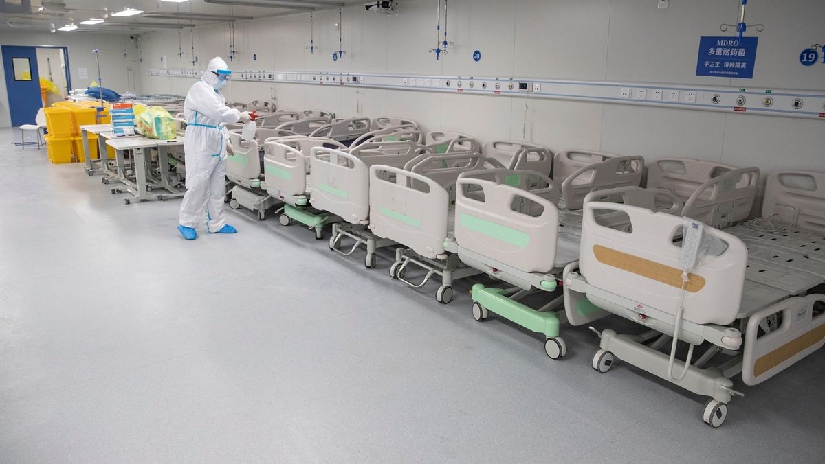 A staff member sprays disinfectant on empty beds after all patients left Leishenshan Hospital