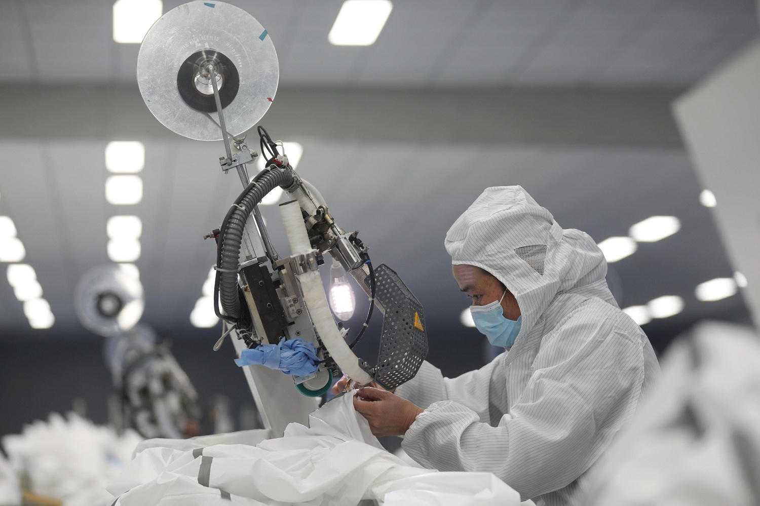 An employee works on a production line manufacturing protective suits at a medical supply factory in Wuhan