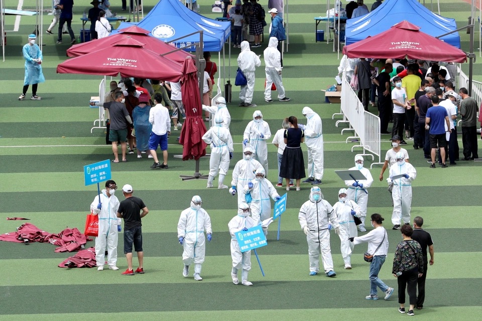 Medical workers in protective suits inside a sports centre carry out nucleic acid tests following a rise in coronavirus cases in Beijing