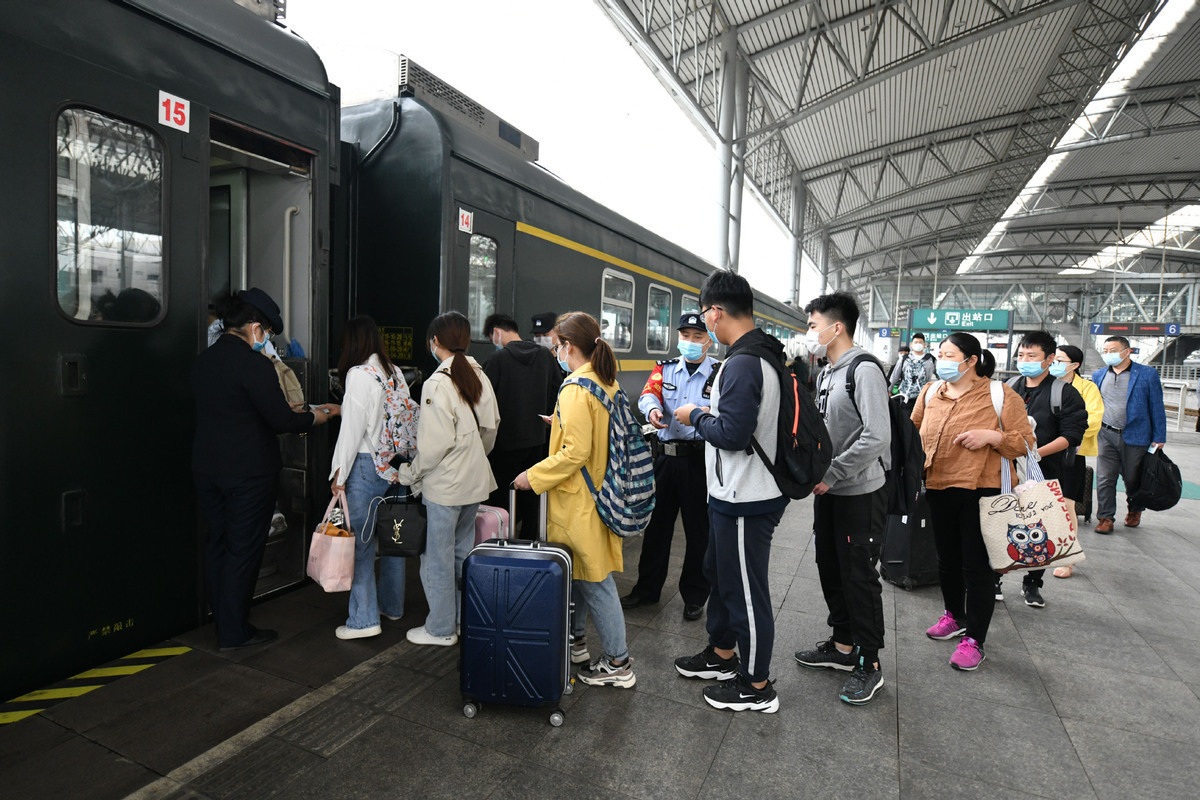 Passengers wait in line to board a train at Fuyang Railway Station in Fuyang East Chinas Anhui province