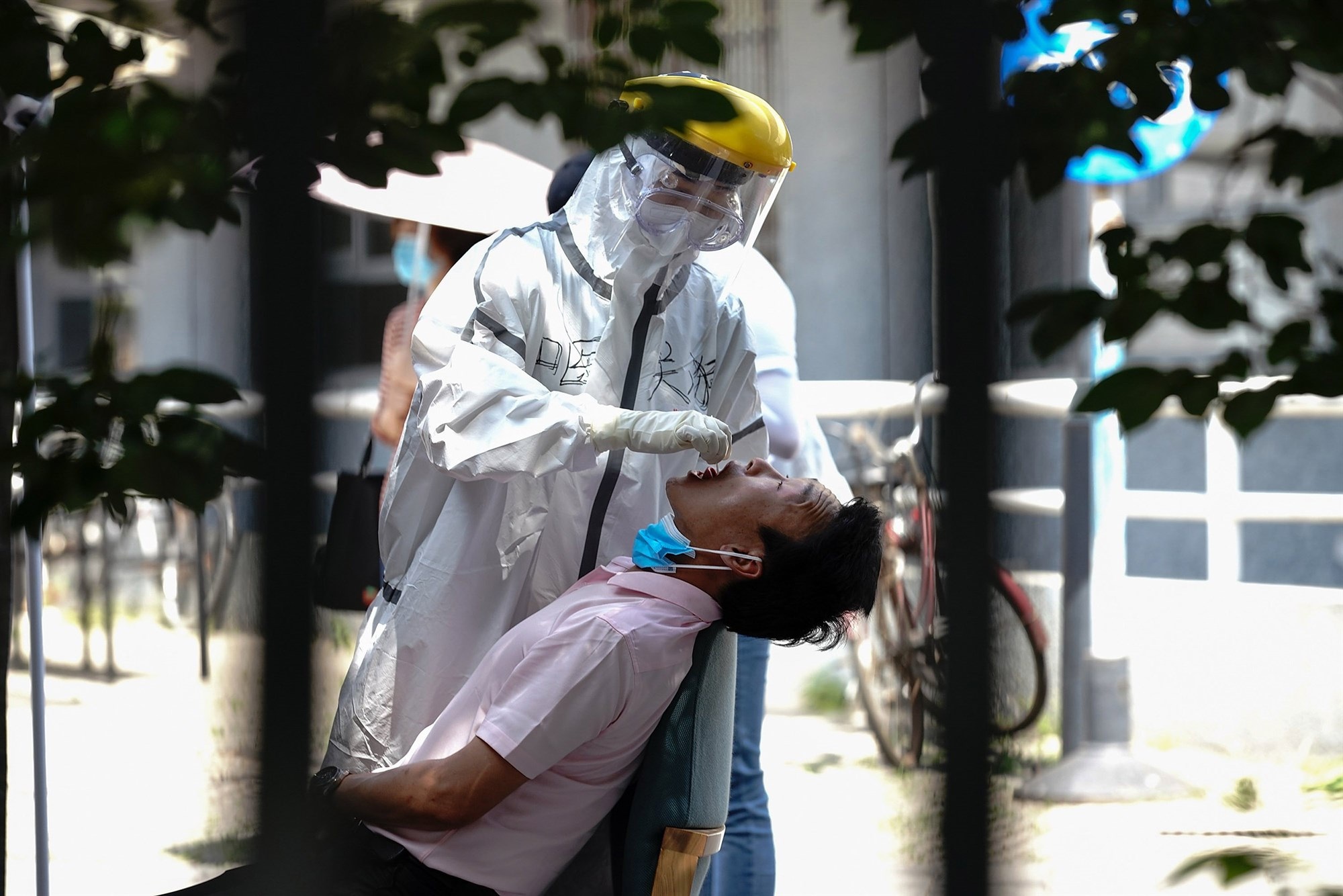 A nurse wearing a protective suit and mask takes a nucleic acid test for COVID 19 from a person who either visited or lives near the Xinfadi market in Beijing