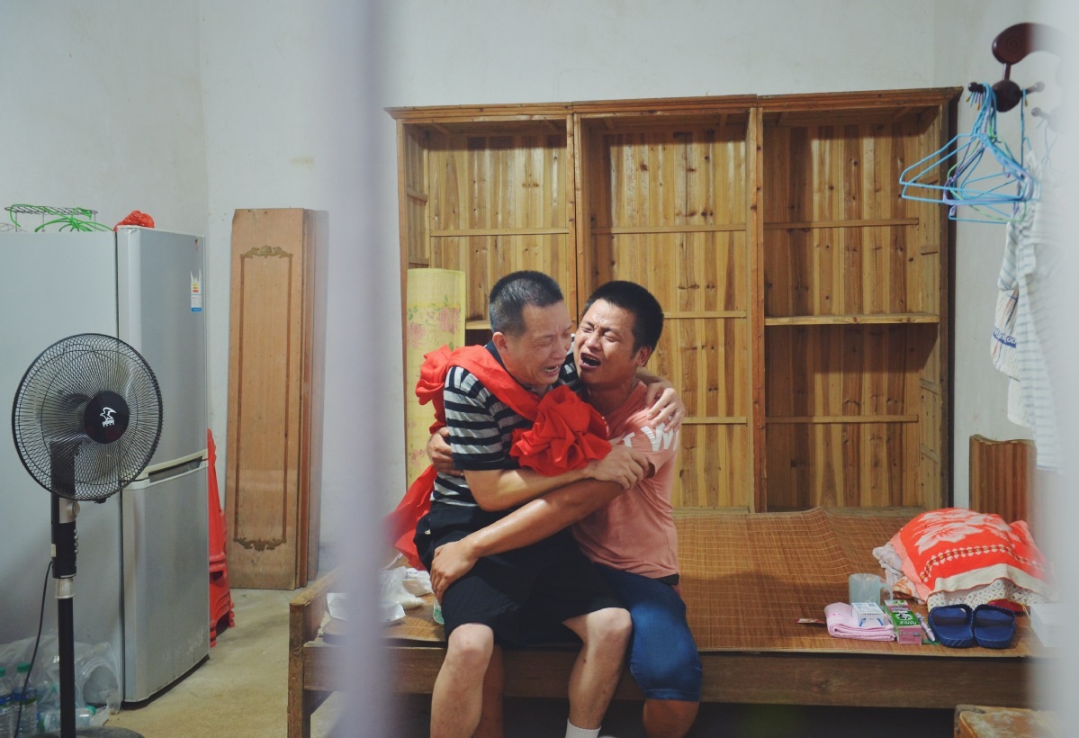 Zhang Yuhuan cries with his son Zhang Baogang at home in Jinxian Jiangxi province