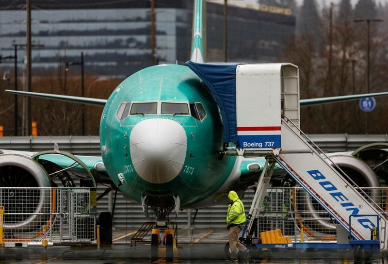 An employee walks past a Boeing 737 Max aircraft seen parked at the Renton Municipal Airport in Renton