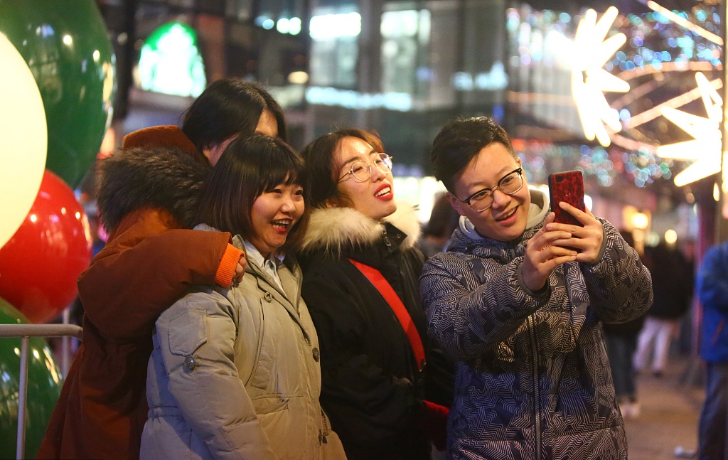 Visitors take selfies while shopping at Sanlitun in Beijing