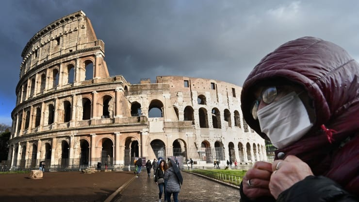 A man wearing a protective mask passes by the Coliseum in Rome