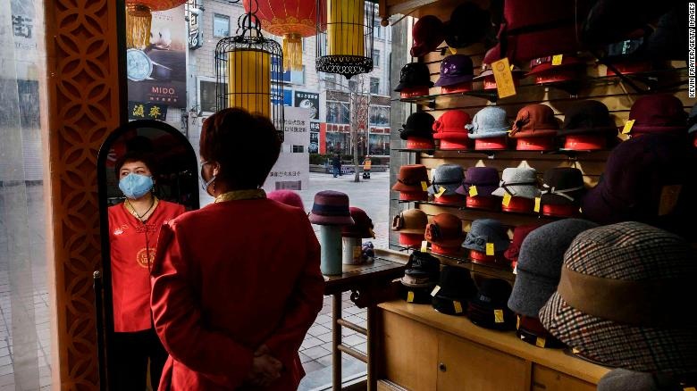 A sales clerk wears a mask as she waits for customers at a hat shop in Beijing