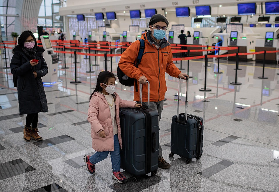 Travellers wearing protective masks walk at the check in area of the Daxing international airport in Beijing on January 21 2020