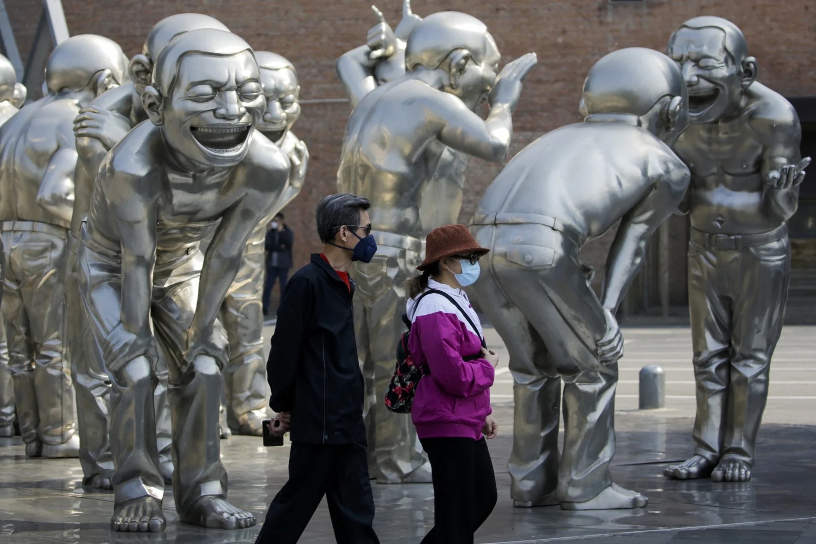 People walk by sculptures on display outside an art gallery in Beijing on April 28 2020
