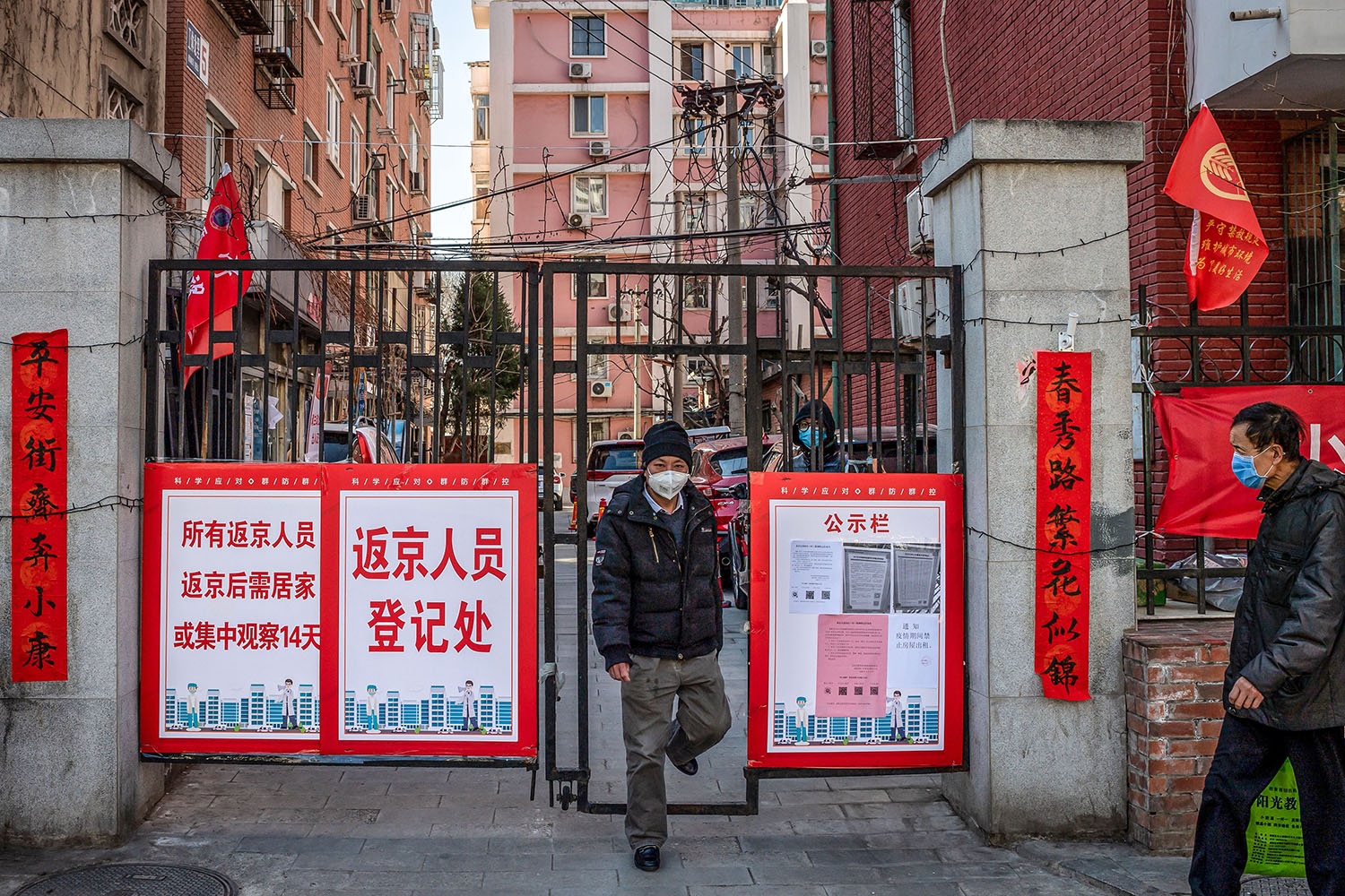 A man wearing a face mask walks out of a residential compound in Beijing